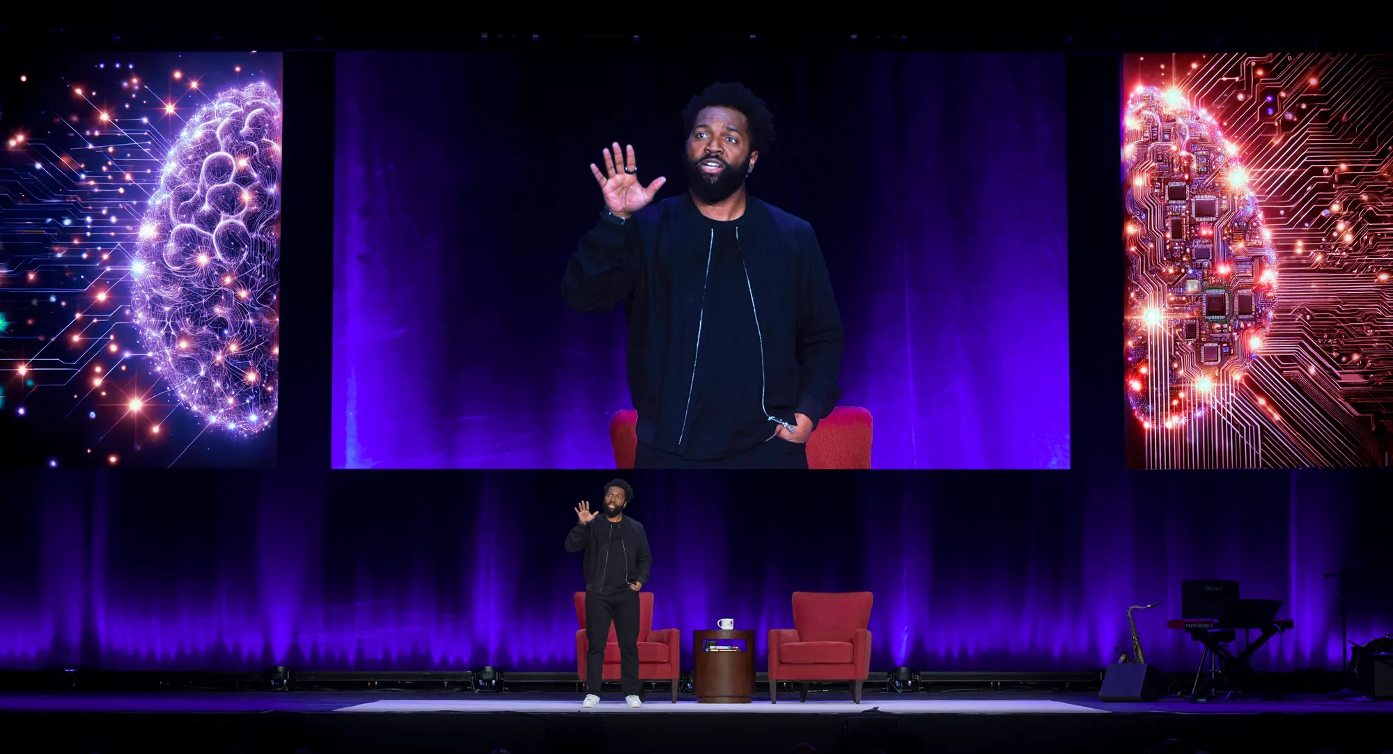 Baratunde Thurston on the Richmond Forum stage beneath a giant illuminated brain