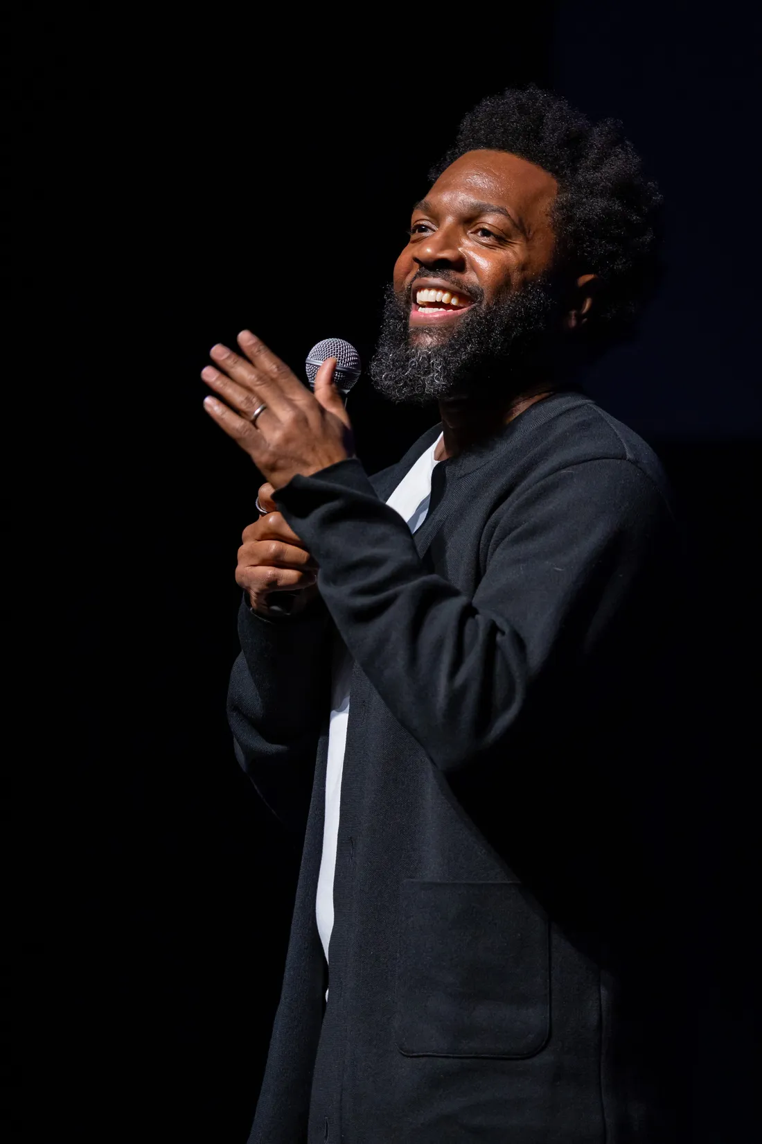 Baratunde Thurston laughing on stage, mic in hand